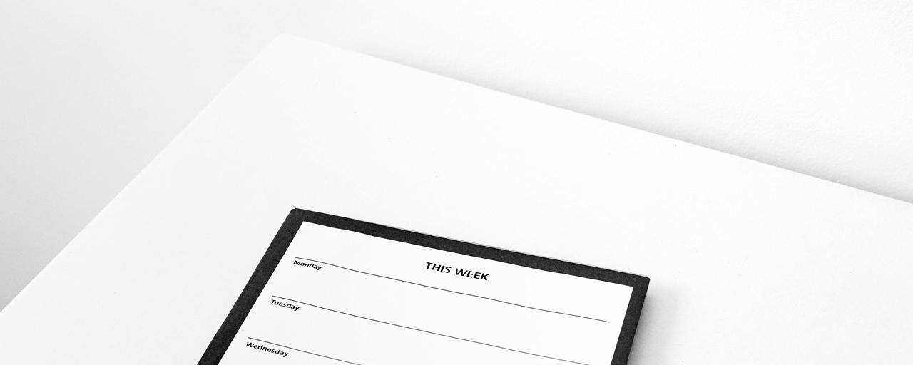 Agenda semanal em branco com uma caneta, sobre uma mesa clara