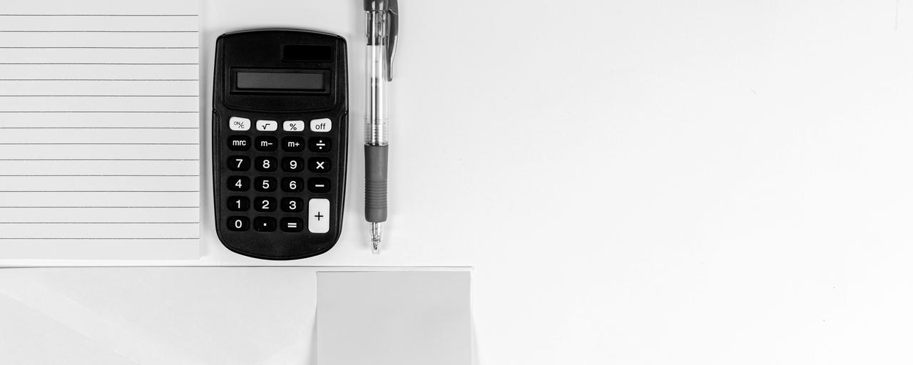 Calculadora, caneta e bloco de notas em branco sobre uma mesa clara